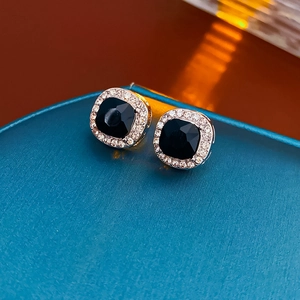Vue détaillée de boucles d'oreilles carrées noires avec diamants sur un écrin bleu