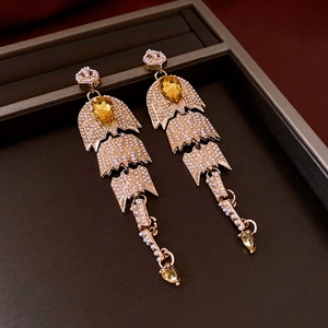 Détail de boucles d'oreilles vintage en arête de poisson avec perles et gemmes jaunes