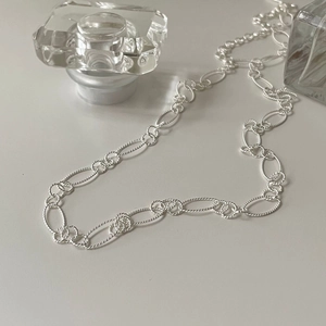 Detailed close-up of s925 silver multi-link chain necklace on elegant glass perfume bottle