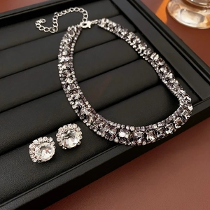 Close-up of sparkling crystal pendant necklace and stud earrings set on black display