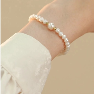 Detail of freshwater pearl bracelet with golden beads on a model's wrist