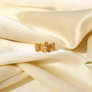 Gros plan sur une bague fleur plaquée or 18k avec émail coloré sur tissu en soie beige