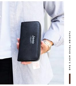 Detail of a large capacity long leather wallet for men in black held in hand