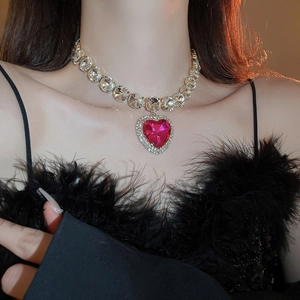 Close-up of a gold necklace featuring a pink heart-shaped crystal pendant on a model