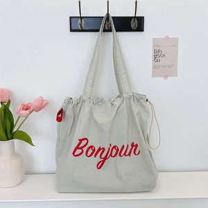 Detail of light grey canvas tote bag with red Bonjour print and drawstring closure design