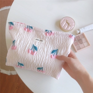 Détail de la trousse à maquillage matelassée blanche avec broderie cerise rose