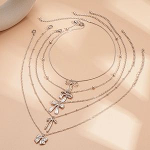 Ensemble de 5 colliers superposés argentés avec pendentifs nœuds et chaînes mélangées