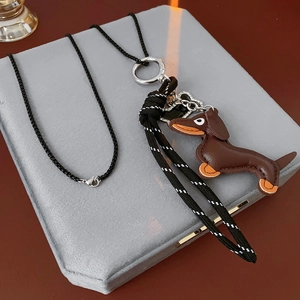 Detail of brown leather dachshund puppy pendant on a black woven necklace cord
