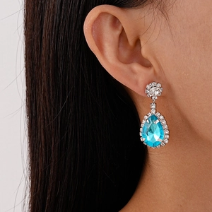 Close-up of teardrop-shaped sky blue crystal earrings with sparkling white rhinestones