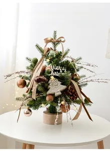 Macro detail of mini Christmas tree with champagne ornaments and warm LED lights