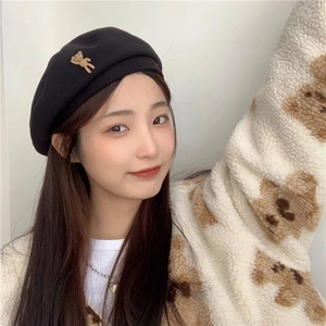 Detail of a black wool beret featuring a cute brown 3D bear accessory on the side