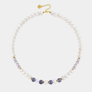 Close-up of beaded necklace with white pearls, purple cat eye stones and gold accents