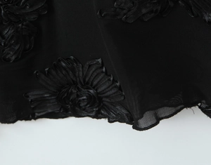 Detailed view of black mesh fabric with handmade 3D ribbon flower applique and boning