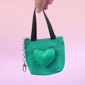 Primer plano de un mini monedero verde en forma de corazón con asas de cinta negras