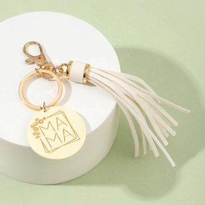 Close-up of golden keychain with white PU tassel and engraved MAMA wooden round pendant