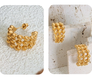 Macro shot of 18K gold plated C-shape earrings with a textured bead weave design
