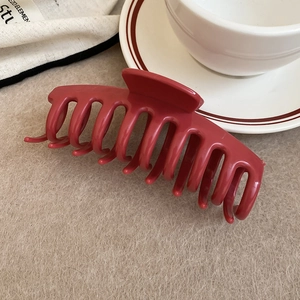 Detail of a large dark red square hair claw clip on a warm aesthetic beige background