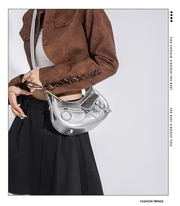 Sac hobo argenté métallisé style motard avec poches zippées porté par un mannequin