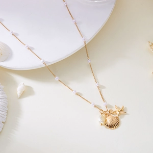 Bohemian gold starfish and shell necklace with white beads on a minimal display