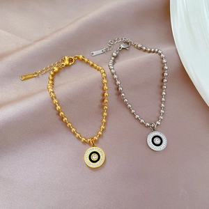 Detail of beaded steel bracelets with zircon stone and Roman numeral charms on silk fabric