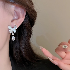 Detail of butterfly stud earring with mother of pearl inlay and teardrop gem pendant