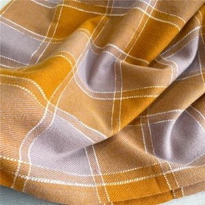 Detailed macro view of yellow and purple checkered scarf featuring soft woven texture
