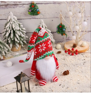 Close-up of knit Christmas gnome with snowflake hat in a snowy festive scene
