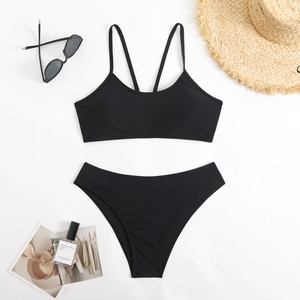 Flat lay of black two-piece bikini with high waist bottoms and beach accessories