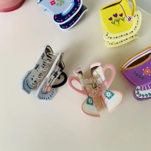 Detail of creative teacup and teapot shaped acrylic hair clips with floral patterns