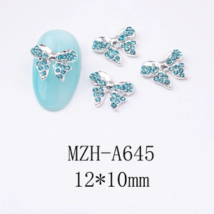 Détail macro d'un bijou d'ongle nœud papillon avec strass bleu clair et base argentée