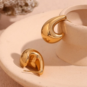 Polished 18K gold plated chunky curved hook earrings shown on a ceramic art tray