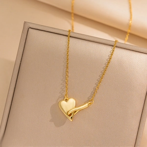 Polished gold heart pendant necklace on beige textured jewelry box for women