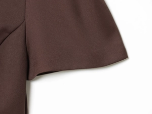 Detail of dark brown twill fabric dress showing clean hemline and textile texture