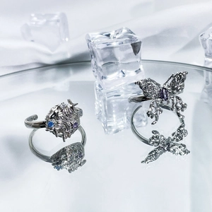 Detailed view of silver butterfly rings with purple gems on reflective mirror and ice