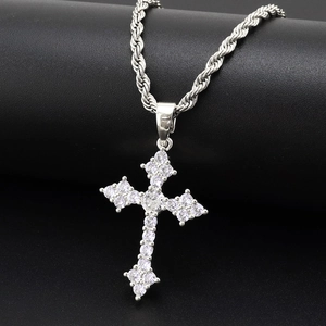 Gros plan du pendentif croix argenté serti de zircons sur une surface noire texturée