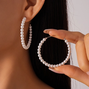 Elegant large hoop earrings with white faux pearls and silver posts on a female model