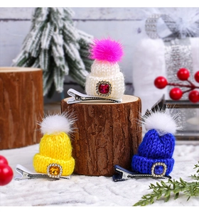 Detailed view of colorful knitted mini Christmas hat hair clips with festive pom-poms