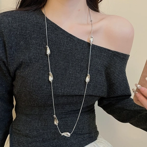 Close-up of long silver liquid metal necklace with irregular beads on model