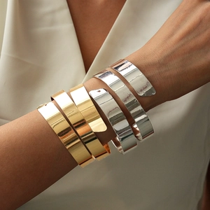 Macro shot of tiered metallic gold and silver wide cuffs with a mirror polished finish