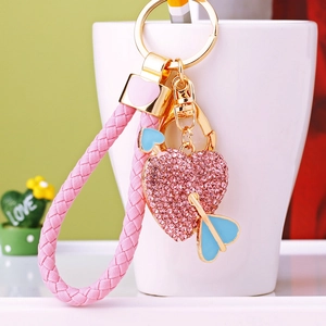 Detail of pink rhinestone heart keychain with cupid arrow and woven leather strap