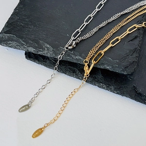 Detailed macro of asymmetric stainless steel mixed chain with gold ball and adjustable clasp