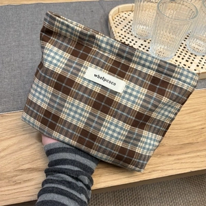 Close-up of a vintage plaid canvas storage pouch with a zip closure and brand label