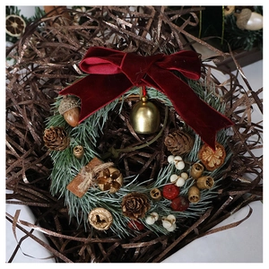 Detail of Christmas wreath with red velvet bow, gold bell, pine cones and artificial berries