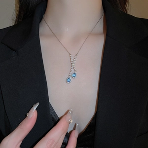 Élégant collier en Y argenté avec pendentifs goutte bleus porté sur un blazer noir