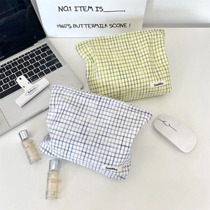 Detail of blue and yellow plaid fabric makeup bags with soft texture and brand label