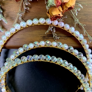 Drei elegante Perlen- und Kristallhaarreifen mit Golddrahtgestell auf einem Holzuntergrund