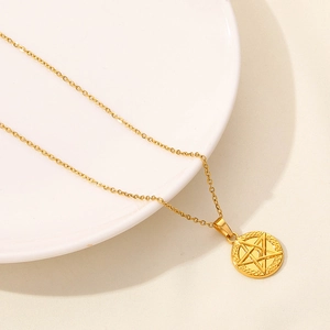 Dettaglio della collana dorata con ciondolo sole e stella su un vassoio di ceramica
