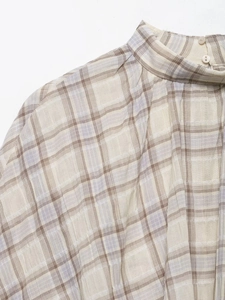 Close-up of the small stand collar and pearl button closure on a plaid blouse