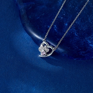 Detail of S925 silver heart necklace with pink zircon cat paw on dark blue background