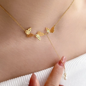 Close-up of gold butterfly necklace with pearl tassel drop on titanium steel chain